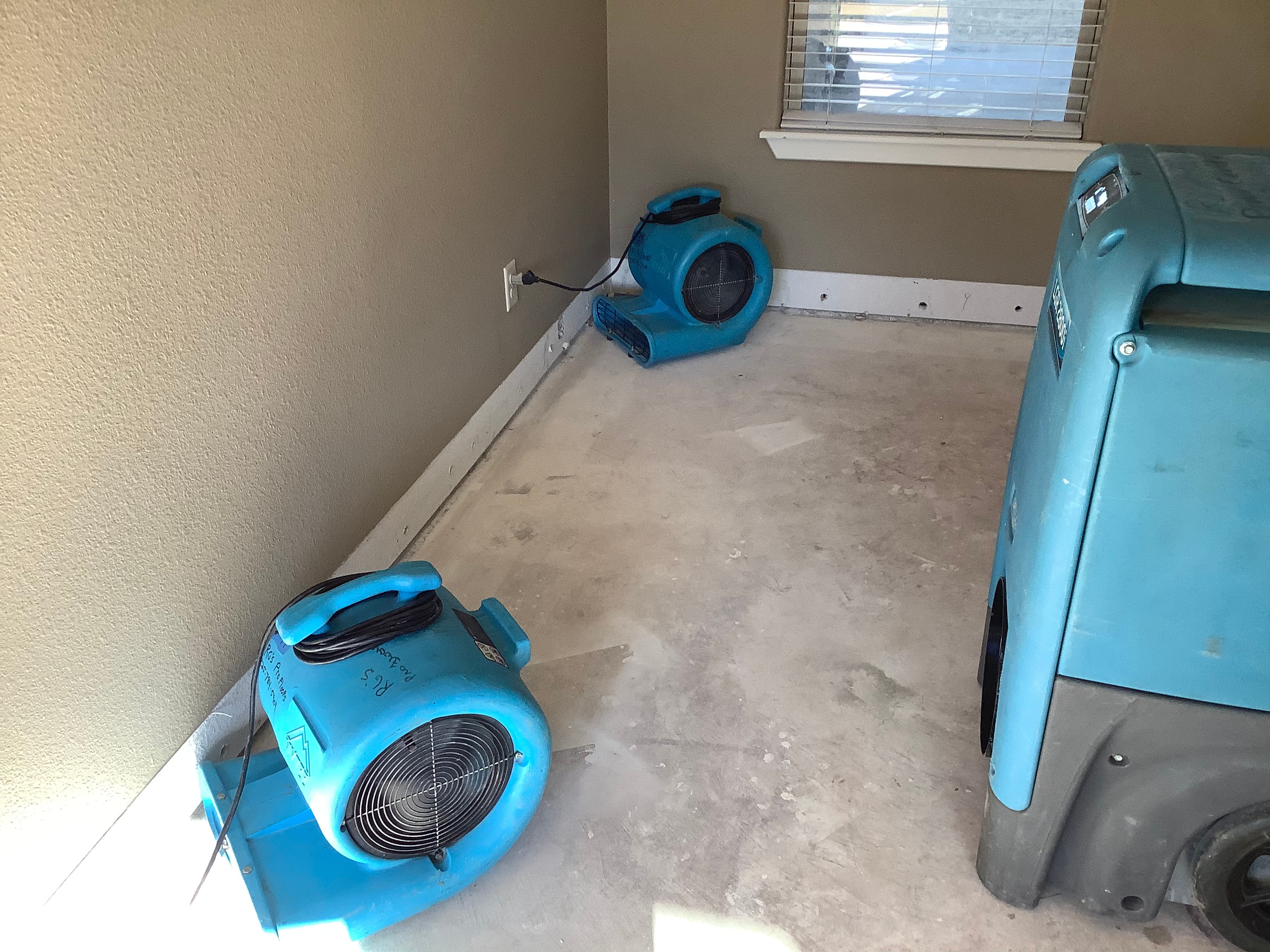 R.G. Pro Floors industrial air mover fans and commercial dehumidifier deployed on bare subfloor during structural drying after water damage in Brownwood TX home