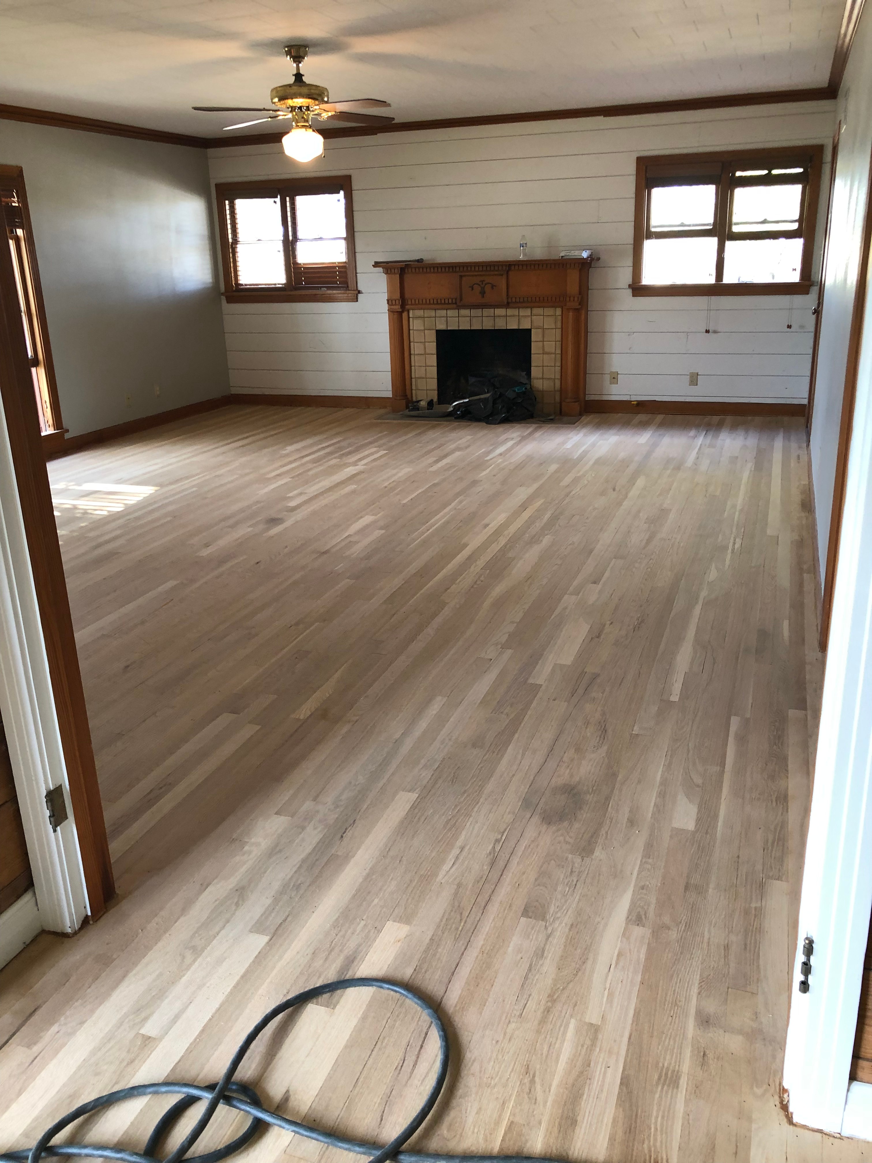 During restoration: Hardwood floor after sanding showing bare natural wood grain with all staining and damage removed
